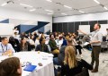 A group of young and emerging professionals seated at round tables in a conference room