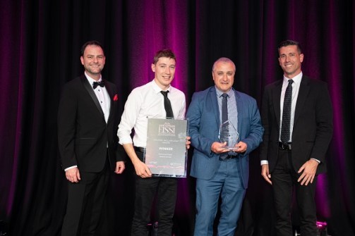 Four people posing with an award