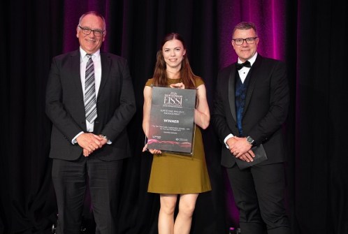 Three people posing with an award