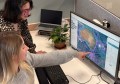 Two women looking at a computer screen, on which is displayed data from AusSeabed, a finalist in the running for one of the Spirit of Service Awards