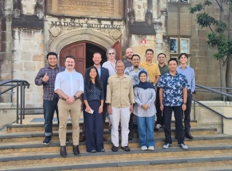 13 participants in the Piksel workshop, standing on the steps of a sandstone building