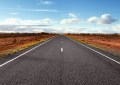 Looking along a highway disappearing into the distance in a desert
