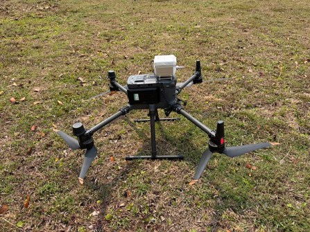 A close-up image of a quadcopter drone stationary on a grass field