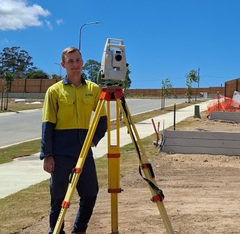 Shaun Sergeant, a TAFE NSW surveying student, standing next to a total station